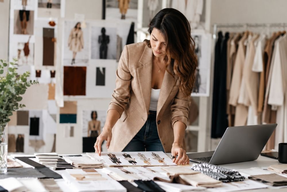 Fashion entrepreneur developing a brand identity with clothing samples, mood boards, and design materials