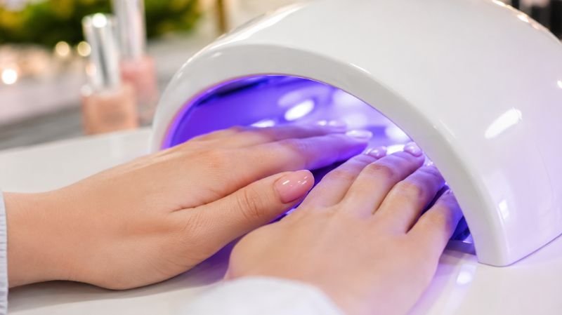 UV lamp curing gel nail polish on fingernails in salon setting