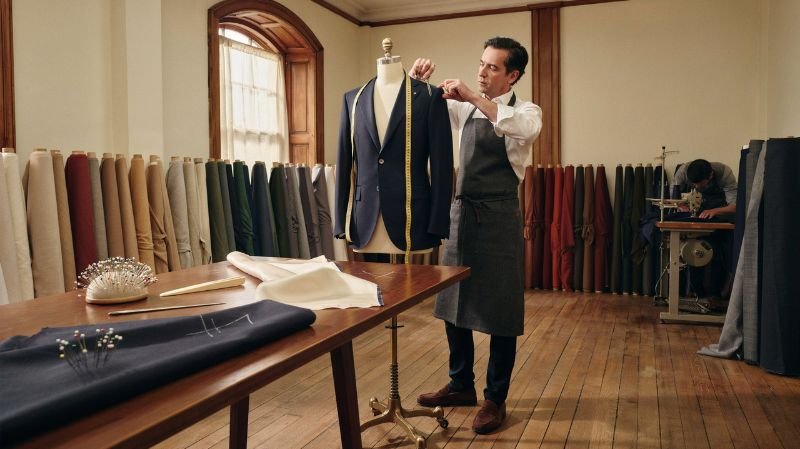 How to Measure for a Suit Jacket: Complete Measurement Tailor checking shoulder fit on a men's suit jacket