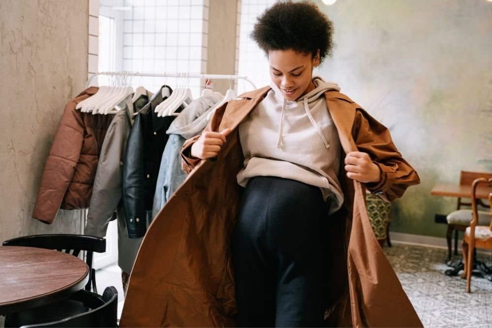 How to Style Your Maternity Photoshoot for a Timeless Look Pregnant woman styling a layered outfit in a walk-in closet